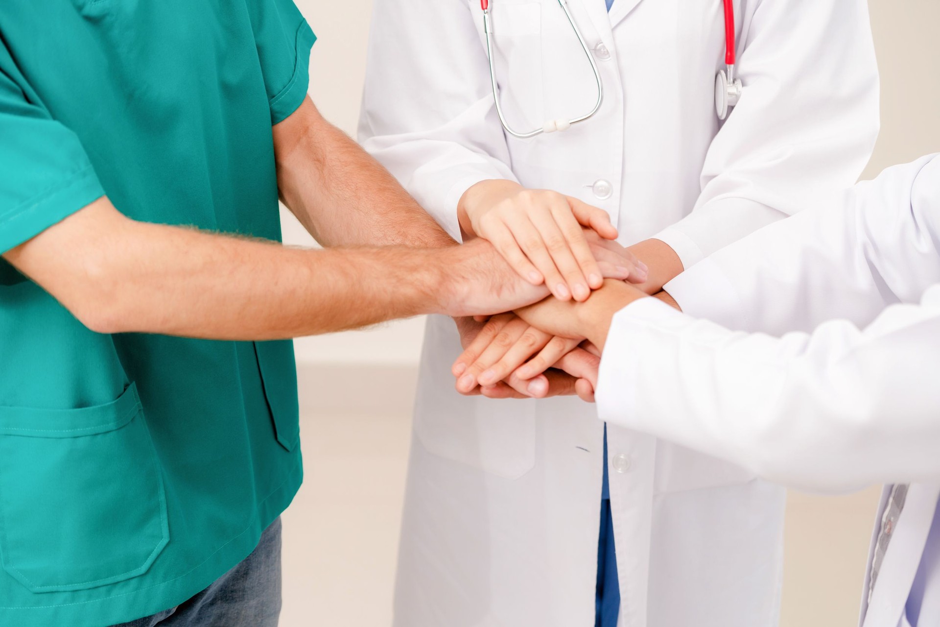 Medical service teamwork - Doctor, surgeon and nurse join hands together.